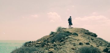 A man standing on top of a hill holding something.