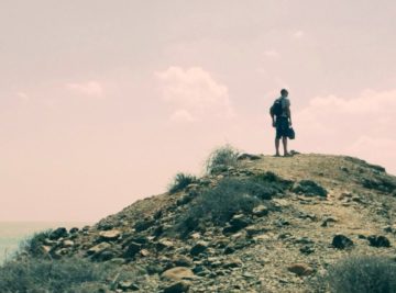 A man standing on top of a hill holding something.